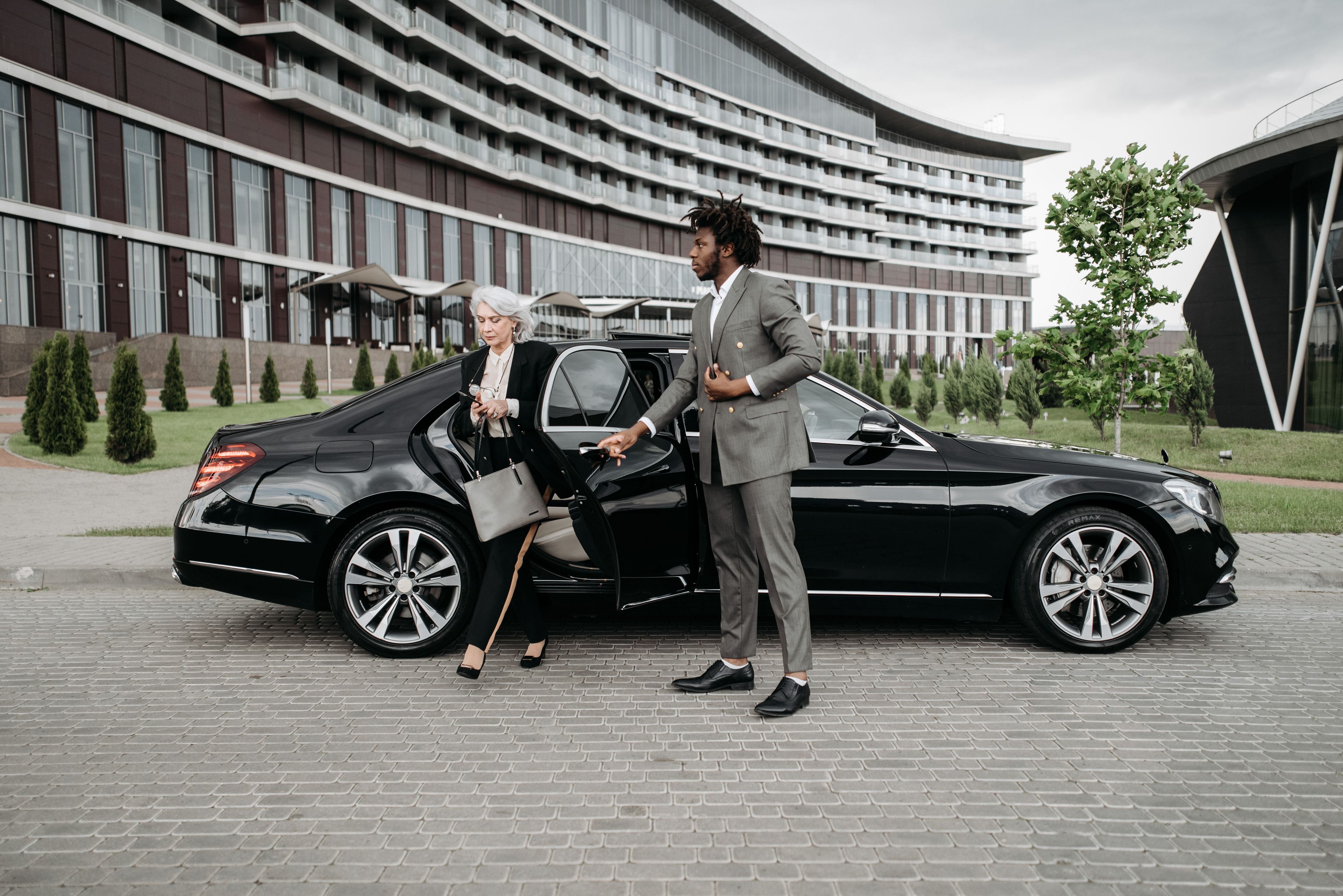 A professional chauffeur waiting beside a luxury car