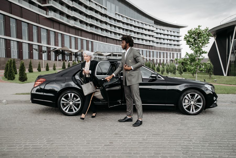 Professional chauffeur waiting beside a luxury car