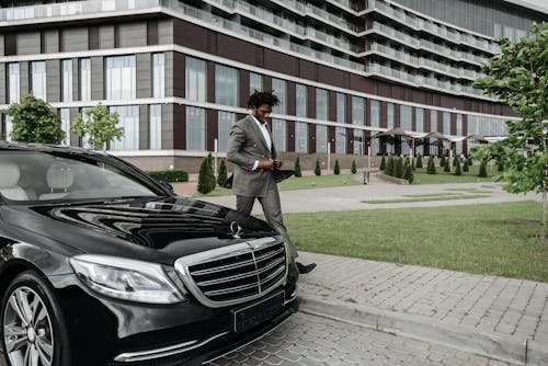 A Businessman Walking beside a Black Car