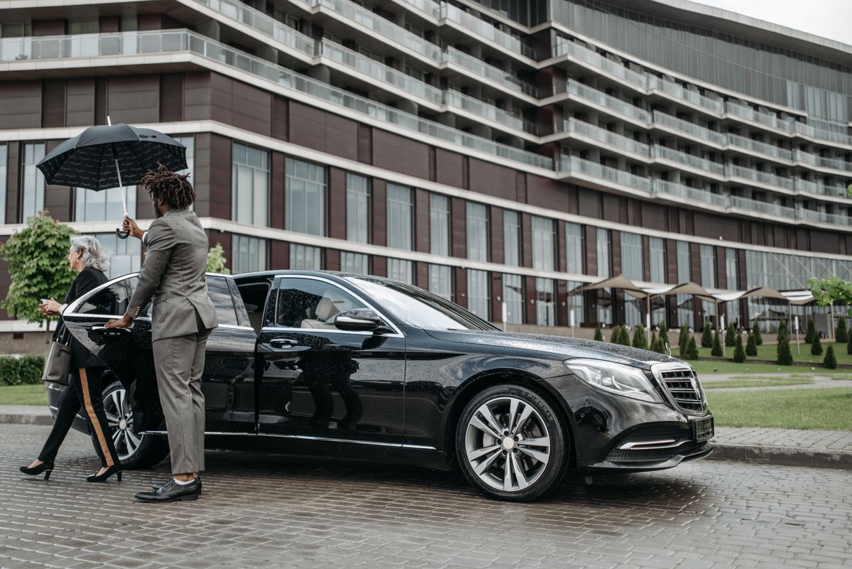 Business traveller stepping out of a chauffeured luxury car