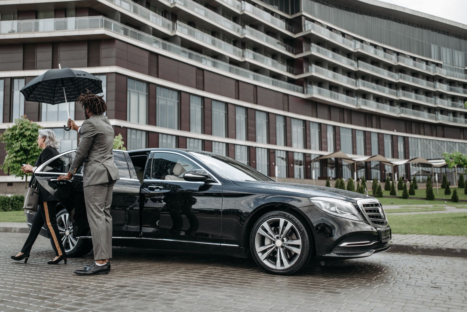 Professional chauffeur assisting an executive beside a black luxury sedan