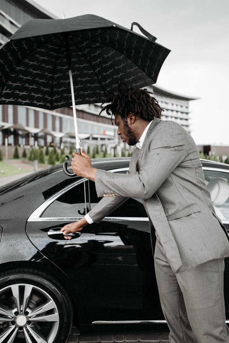 A Man In Gray Suit Opening The Door Of A Black Car