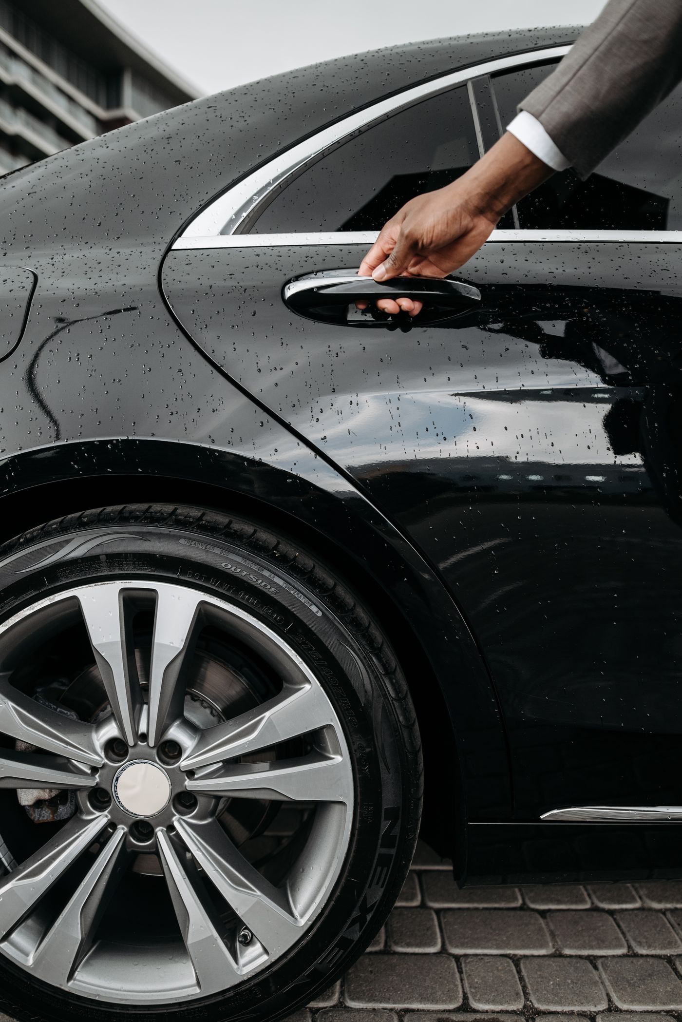 Chauffeur opening the rear door of a black luxury sedan