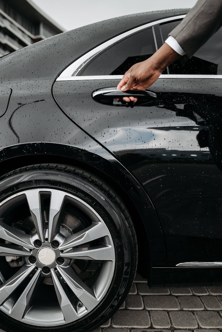 Close-Up Shot Of A Person Opening The Door Of A Black Car