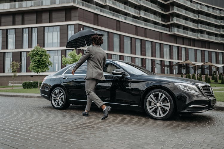 A Man In Gray Suit Opening The Door Of A Black Car