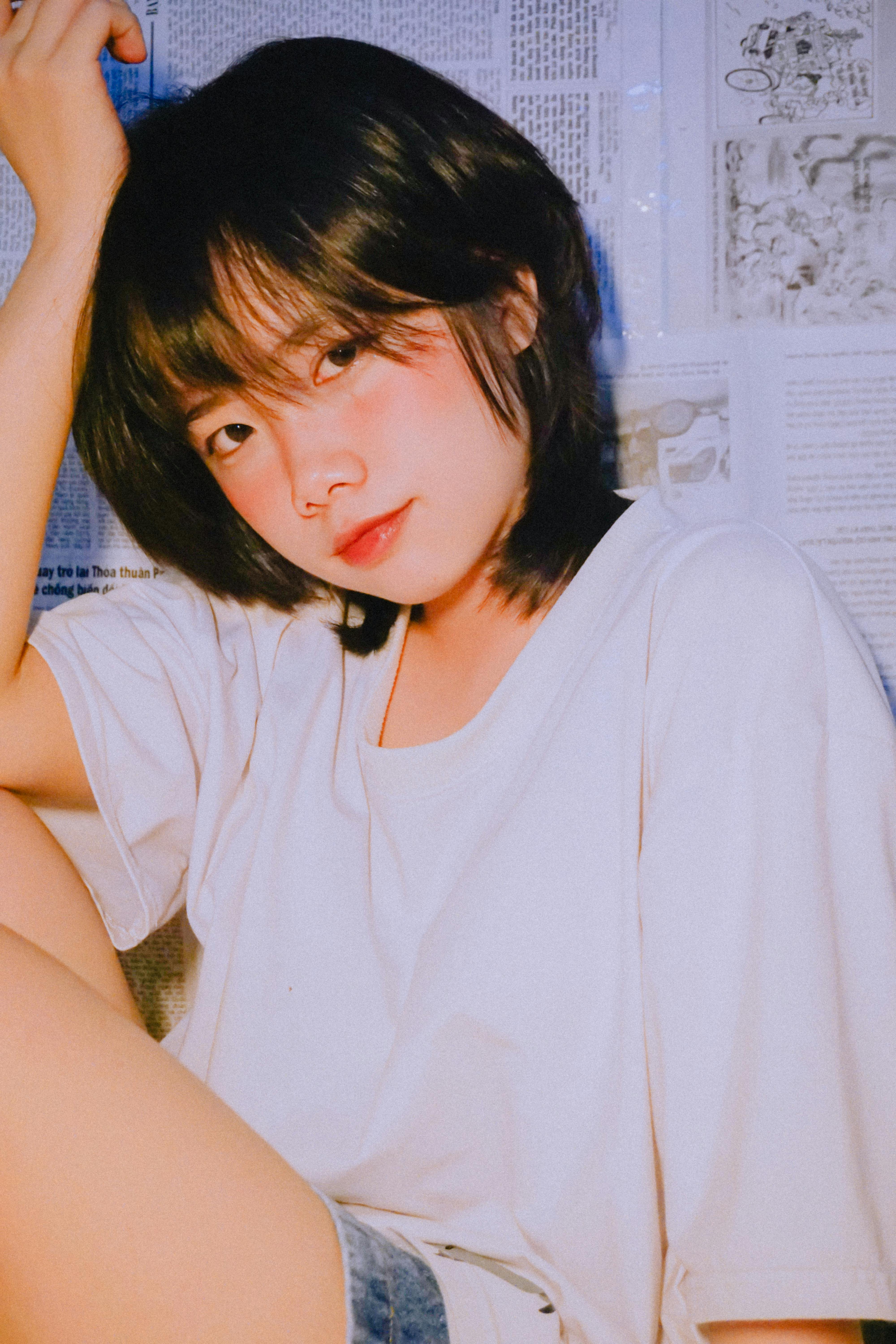 Casual portrait of a young woman with dark hair wearing a white shirt, indoors.