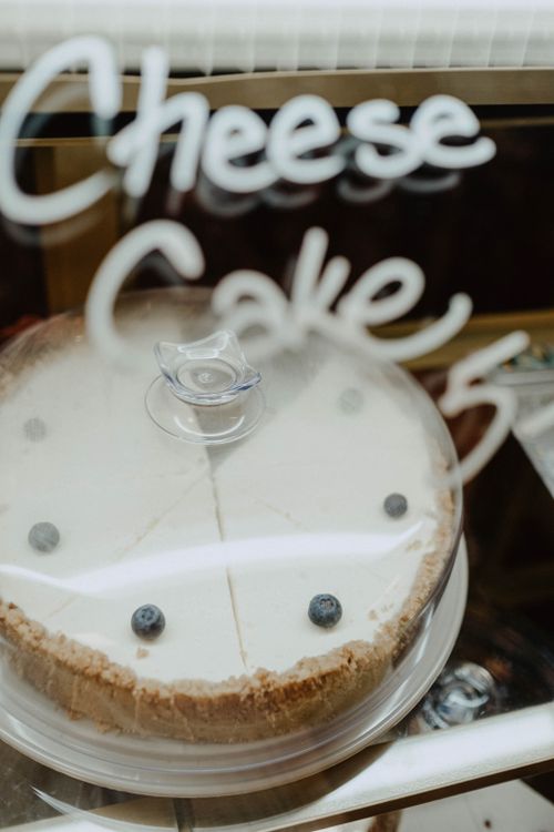 Free A fresh cheesecake topped with blueberries, under a glass cover, labeled 'Cheesecake'. Stock Photo