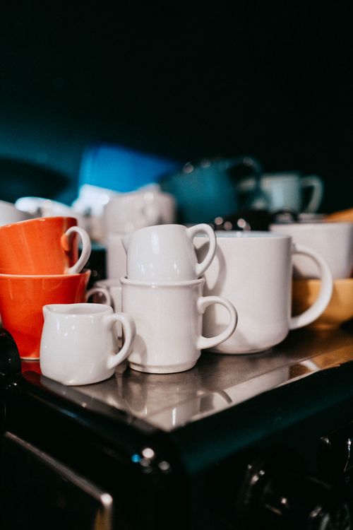 Free Collection of colorful ceramic cups stacked on a kitchen counter with a blurred background. Stock Photo