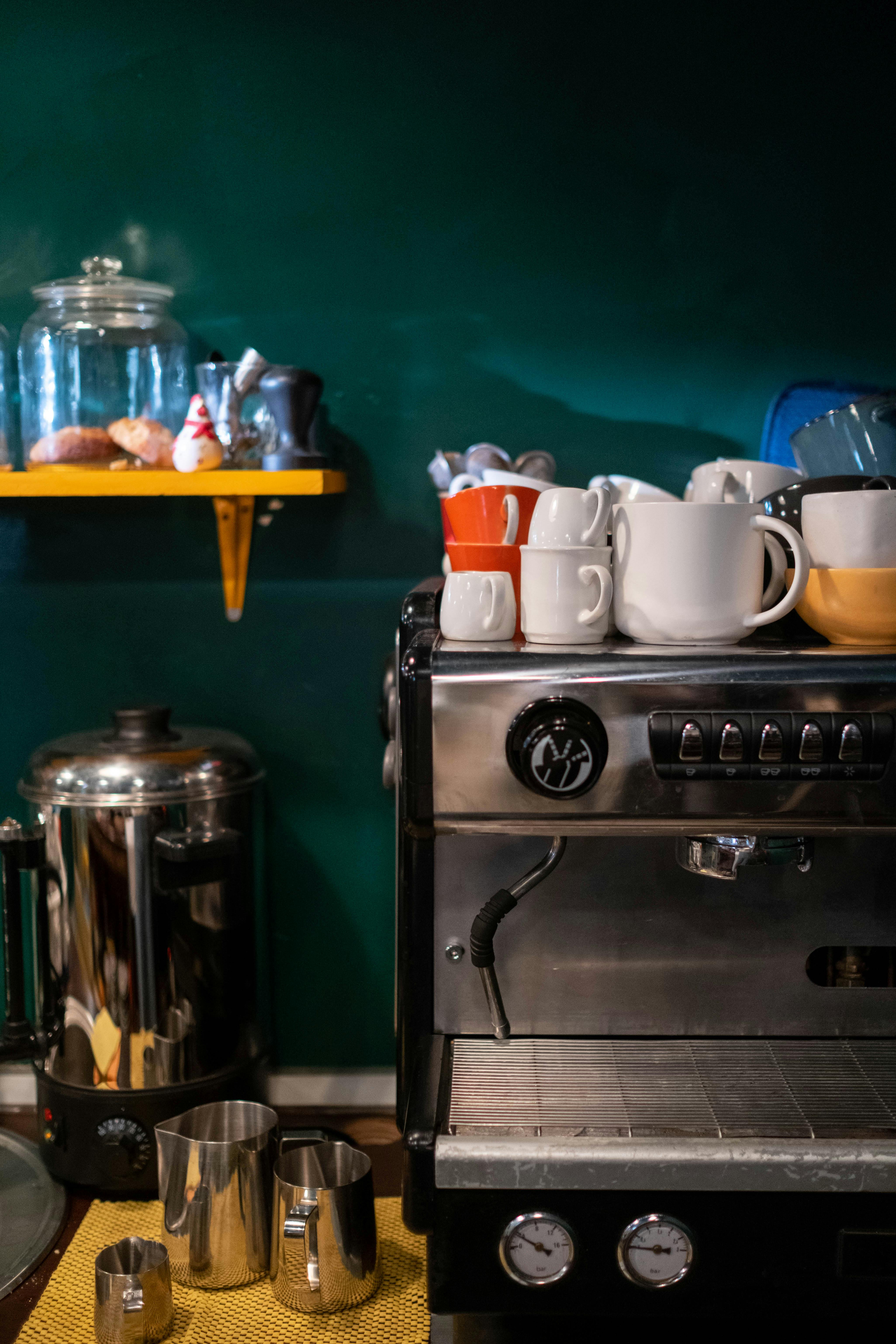 A coffee machine with various mugs in a cozy kitchen setting, perfect for cafe themes.