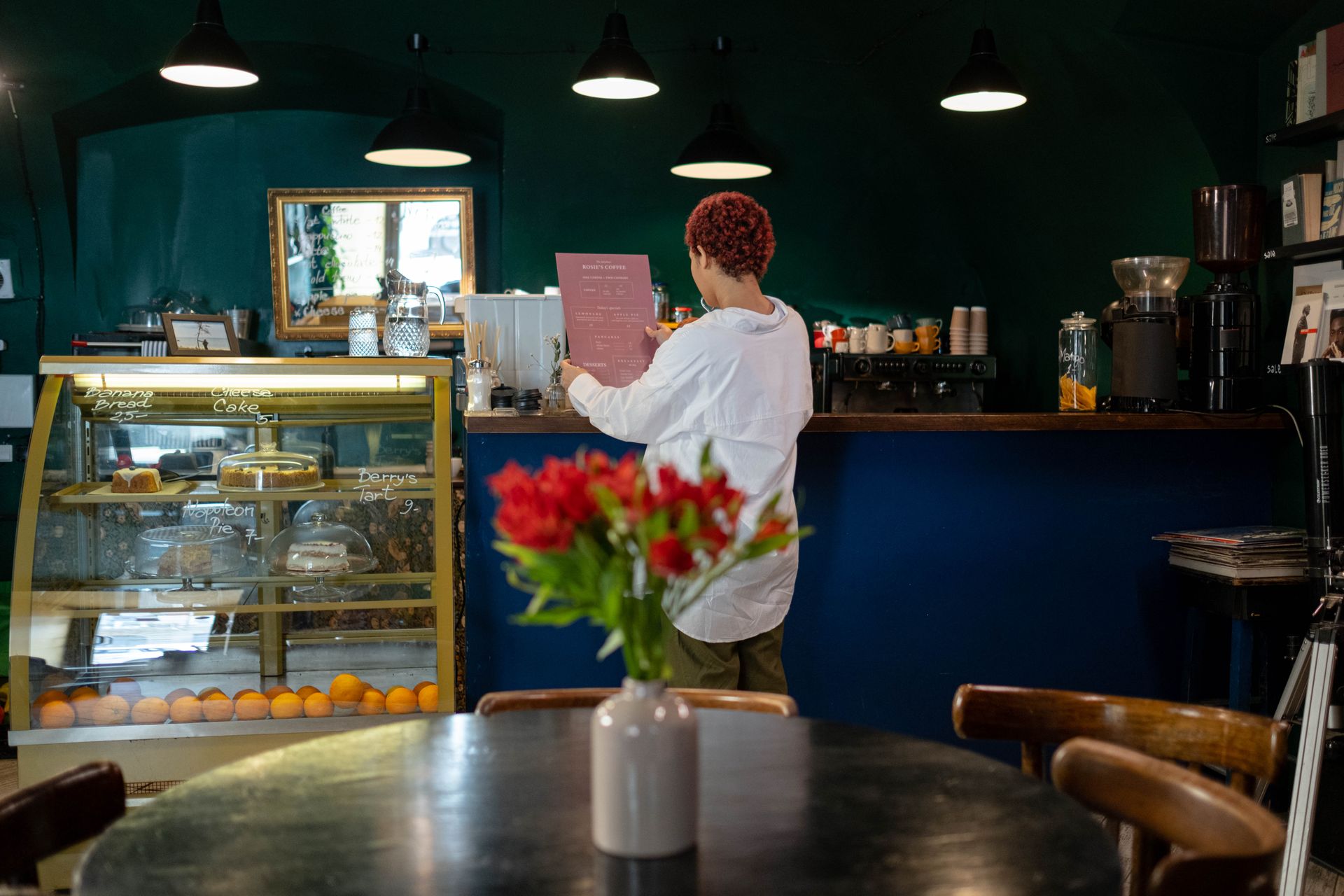 Woman in White Long Sleeve Shirt Standing beside Blue Counter