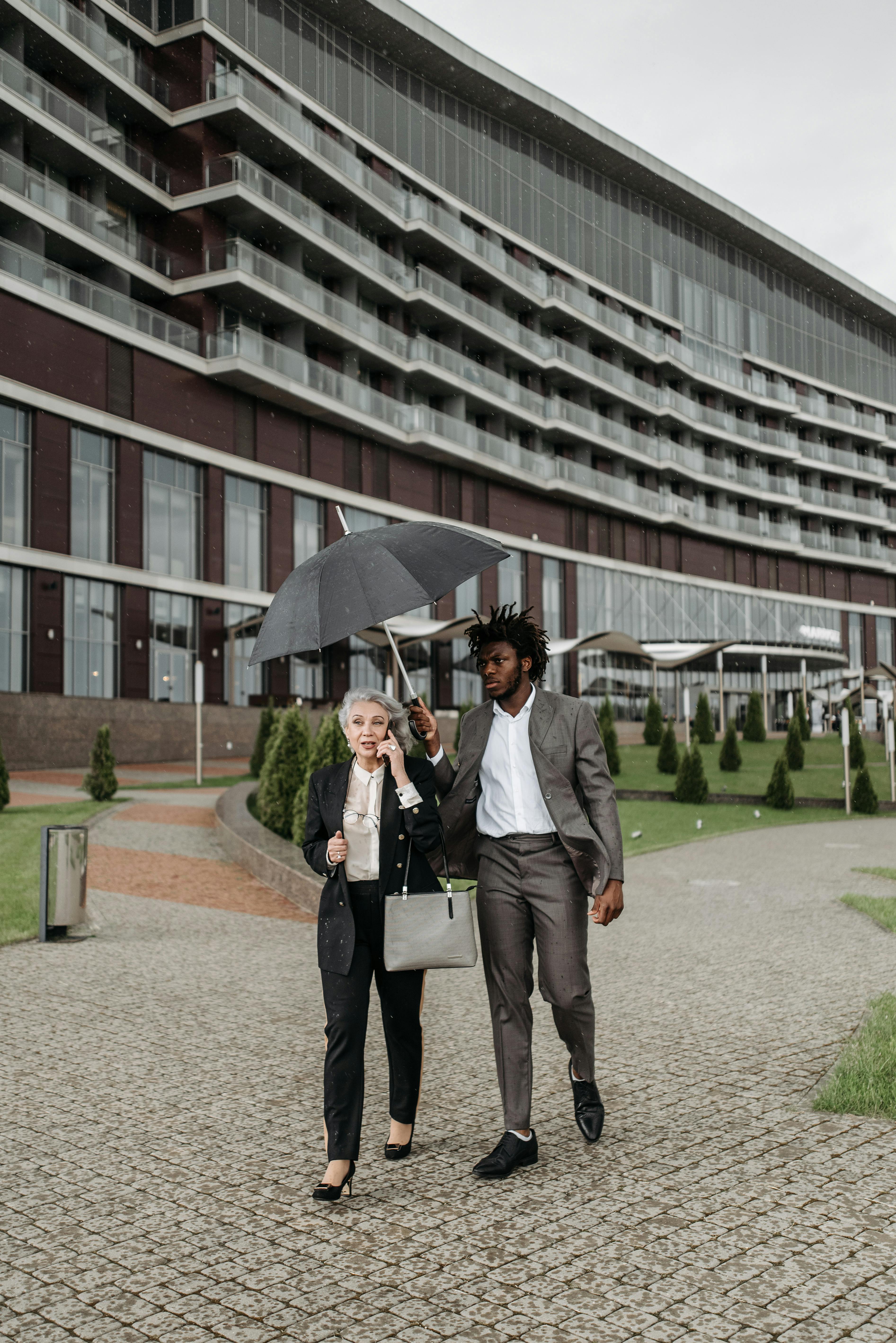 Man in Gray Suit Jacket Holding Umbrella Beside a Woman Free