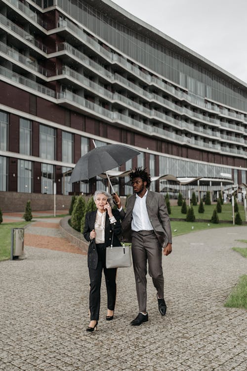 Man Holding Umbrella While Walking with a Woman