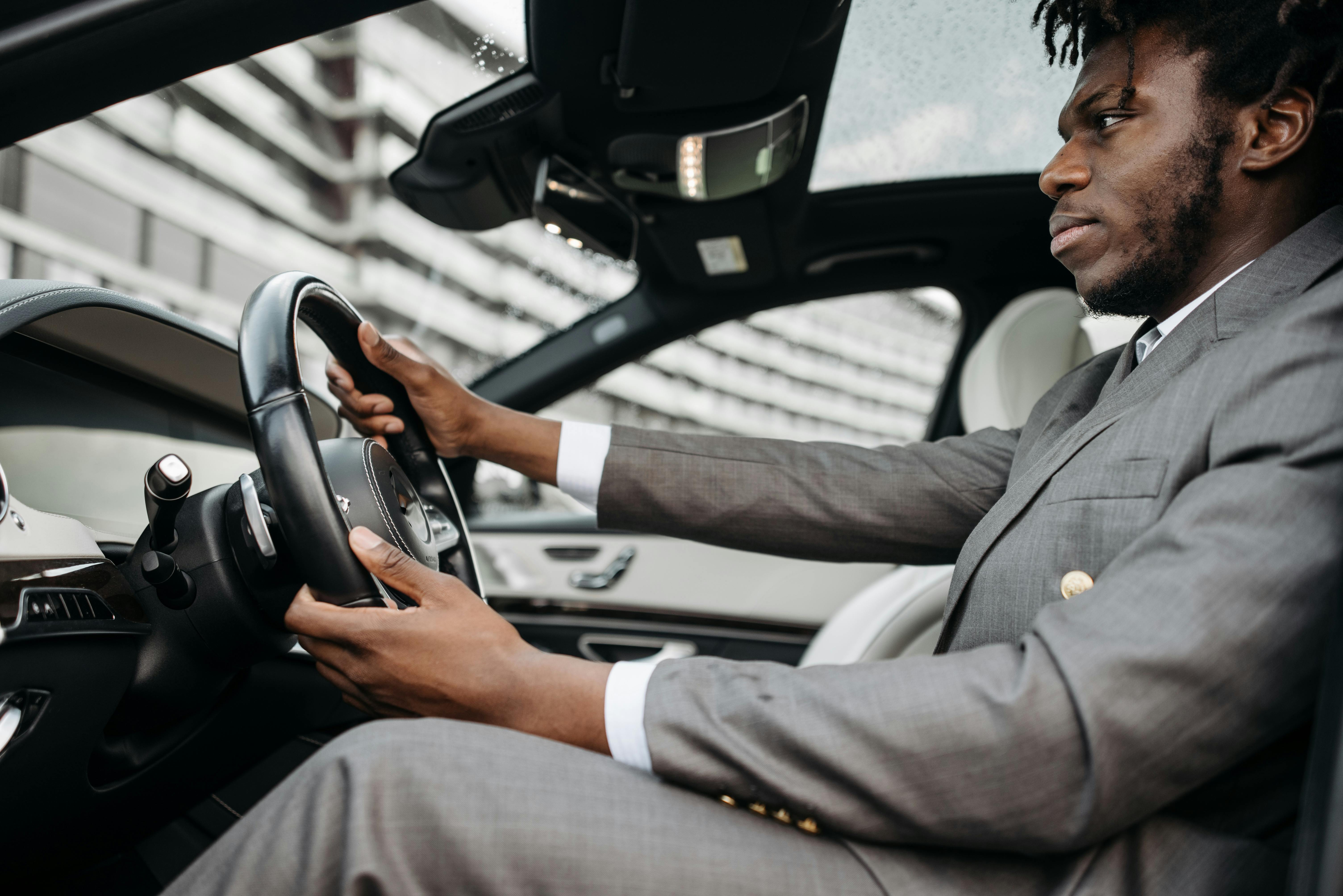 man in gray suit driving a car