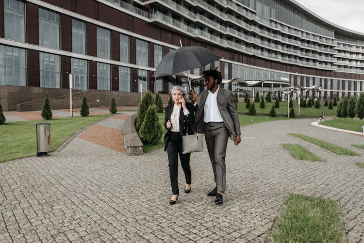 Man In Gray Suit Jacket Holding Umbrella Beside A Woman