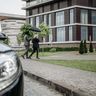 Two business professionals walk together under a black umbrella outside a modern glass office building.