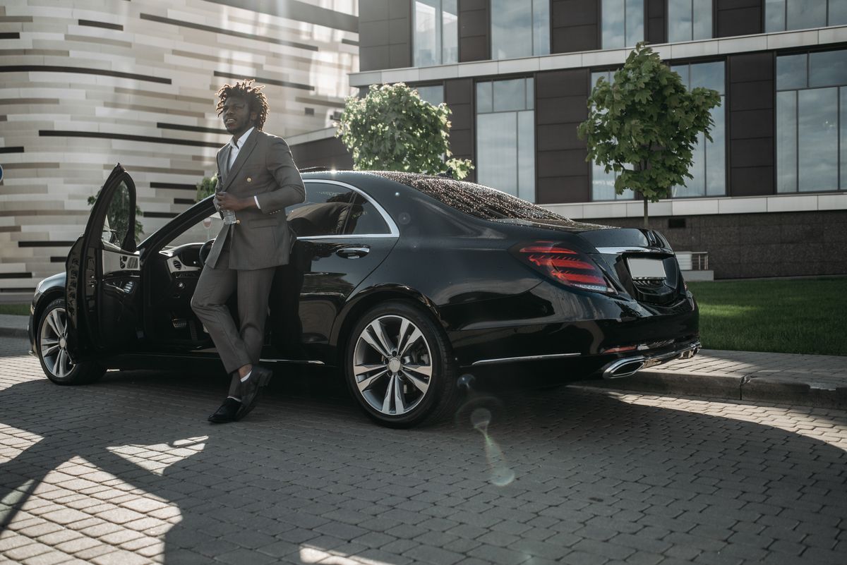 Businessman in a suit stepping out of a luxury car outside a venue