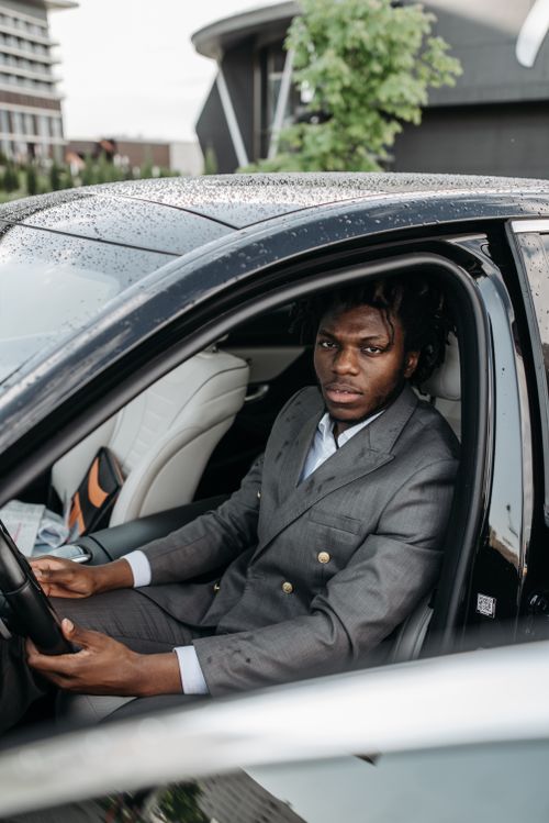 Free Stylish man in a gray suit seated in a luxury car, ready for a drive. Stock Photo