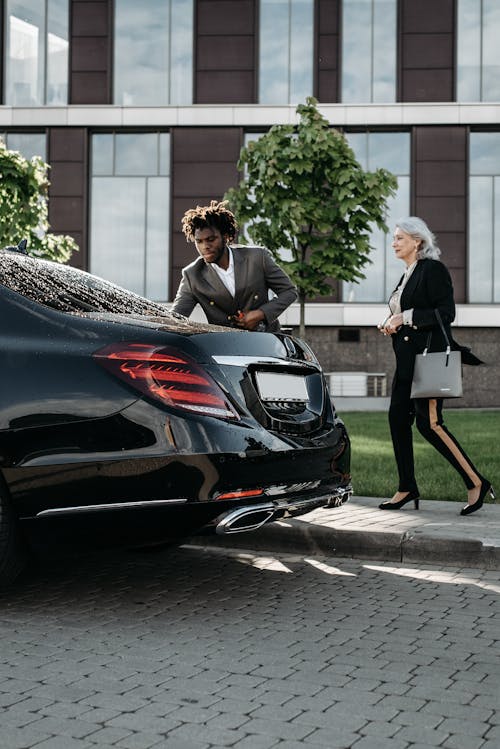 A Man in Black Suit Standing Beside Black Car