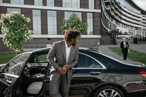 Man in Suit Jacket and Gray Pants Standing Beside Black Car