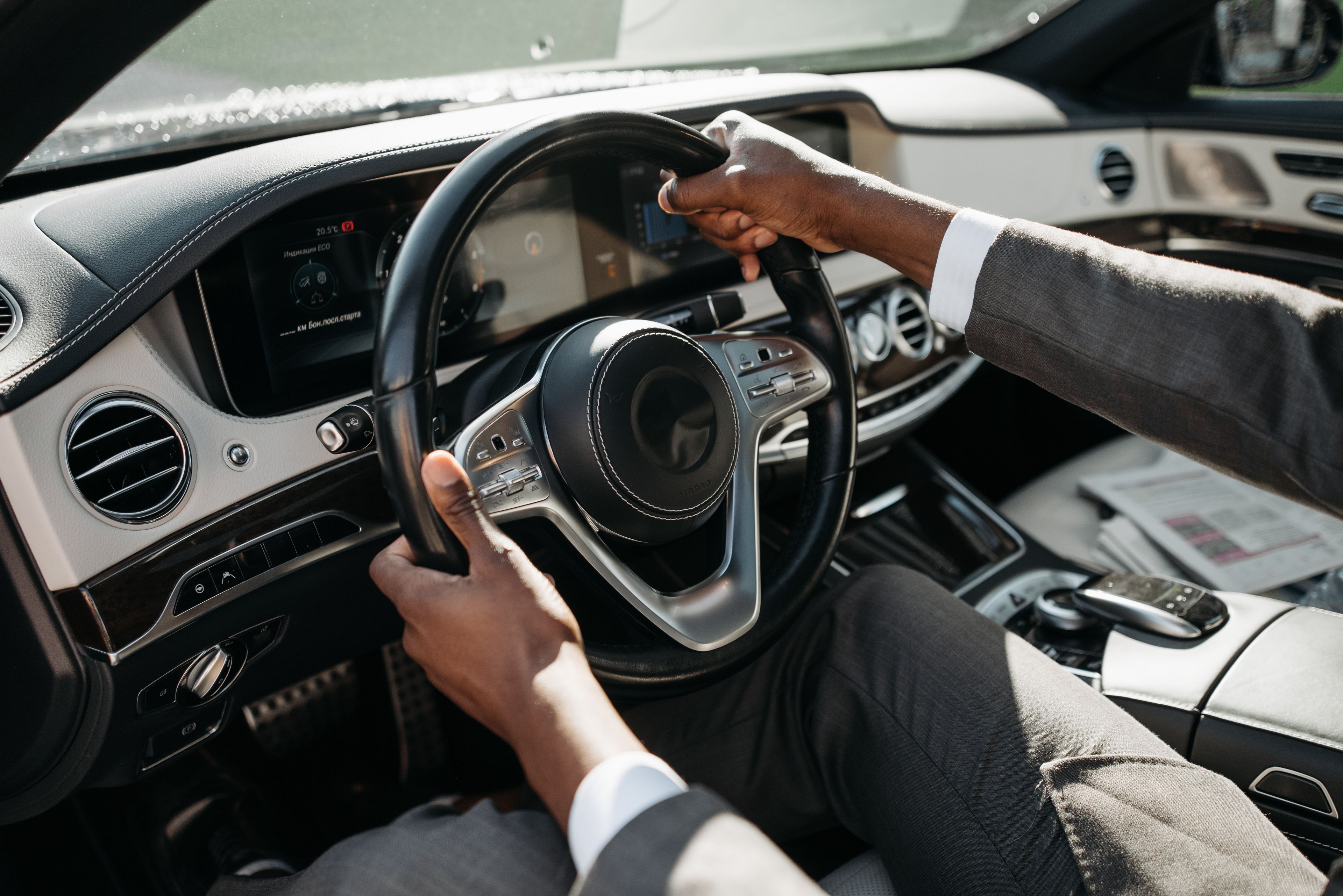 A professional chauffeur waiting beside a luxury car