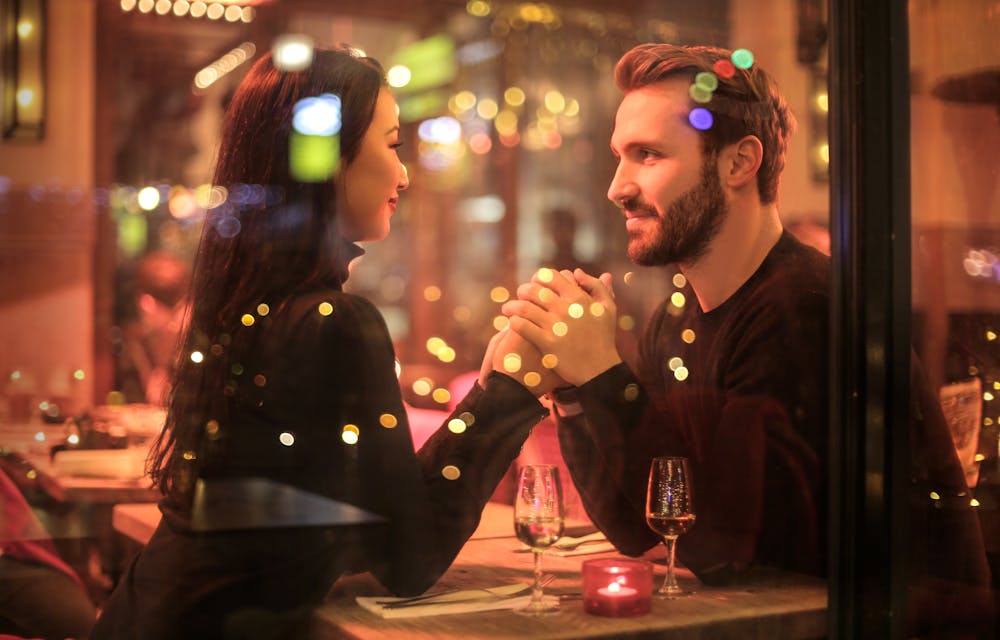 A couple holding hands at a restaurant. | Photo: Pexels