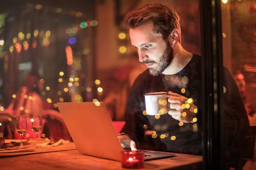 Free Man Holding Mug in Front of Laptop Stock Photo