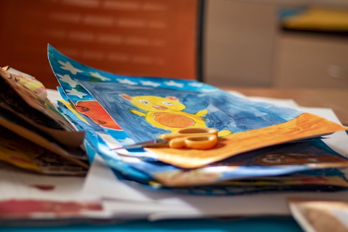 Cheerful children's artwork of a yellow teddy bear surrounded by crafting supplies