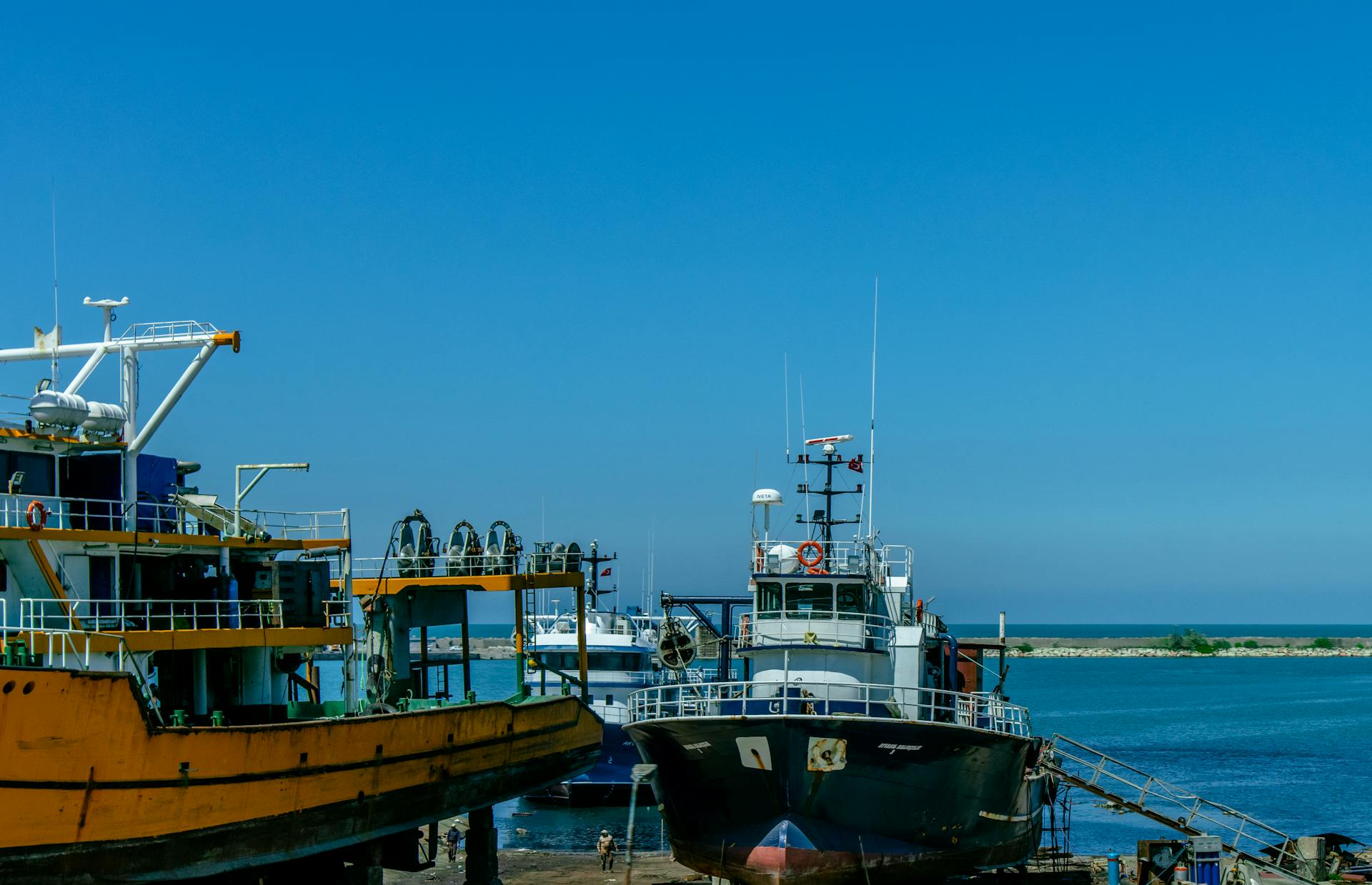 Vibrant scene of fishing boats docked at Trabzon harbor, Turkey under a clear blue sky.