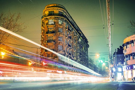 Long exposure of Wukang Mansion in Shanghai with vibrant traffic light trails at night.
