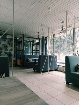 A stylish modern café interior featuring glass panels, sofas, and ceiling lights. Ideal for architectural design concepts.