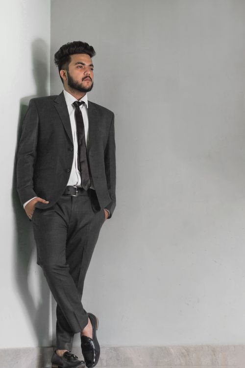 Free Asian man in a suit leaning against a wall, showcasing modern fashion and confidence. Stock Photo