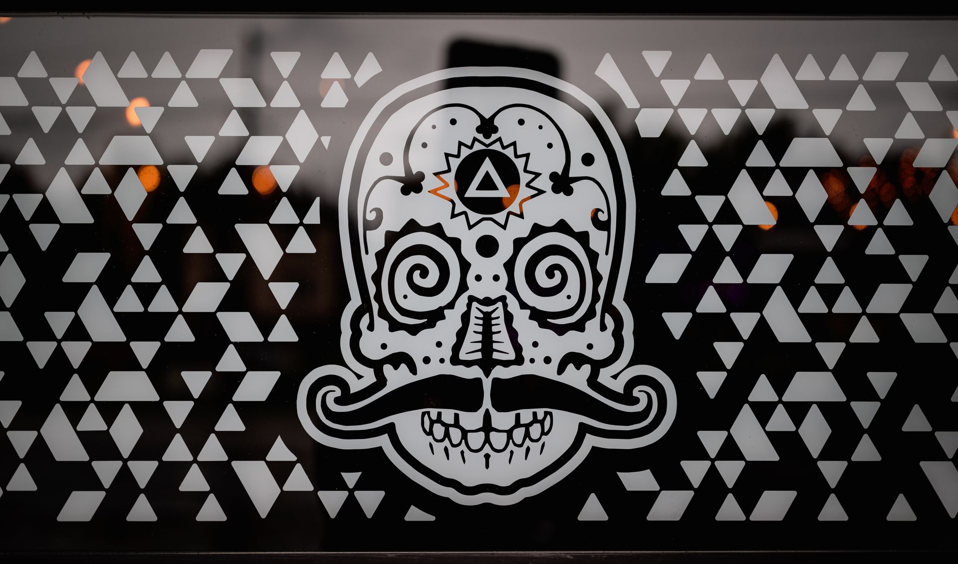 Intricate skull design with triangular geometric patterns on a window, creating a compelling artistic effect.