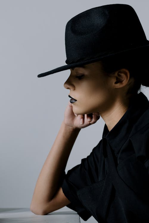Free Side View Shot of a Sad Woman in Black Hat Looking Down Stock Photo