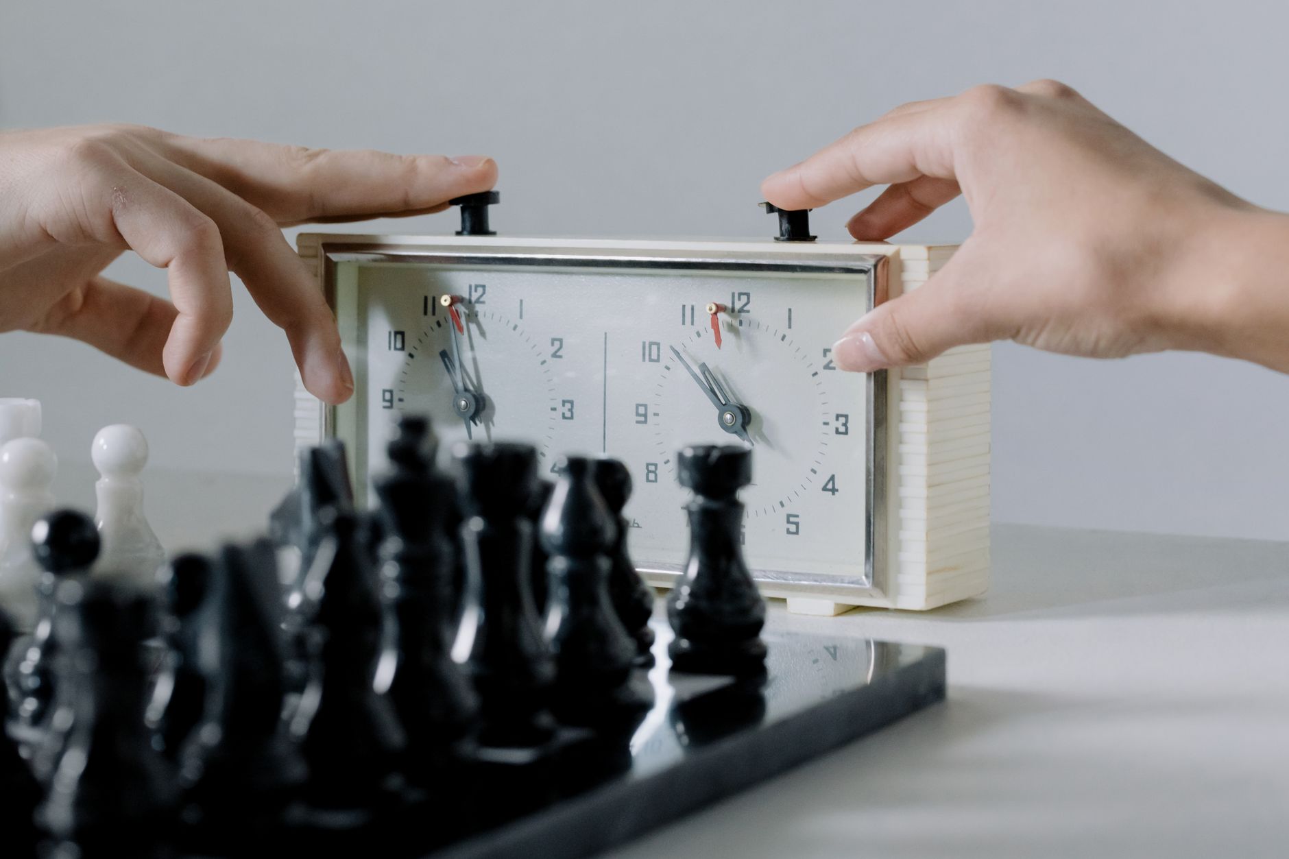 Close-up of hands pressing chess clock during an intense board game session.