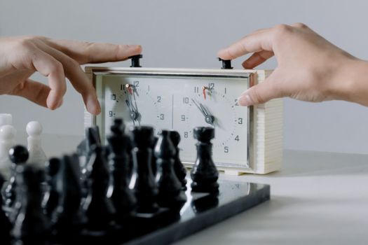 Close-up of hands pressing chess clock during an intense board game session.