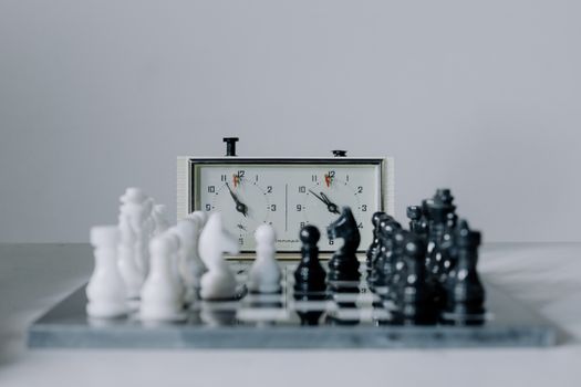 Close-up view of a chess match featuring black and white pieces and a chess clock.