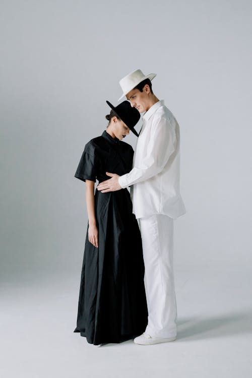 Woman in Black Dress Standing beside a Man in White Long Sleeve Shirt