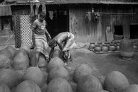 Grayscale Photo of Man and Woman Sitting on Round Wooden Table