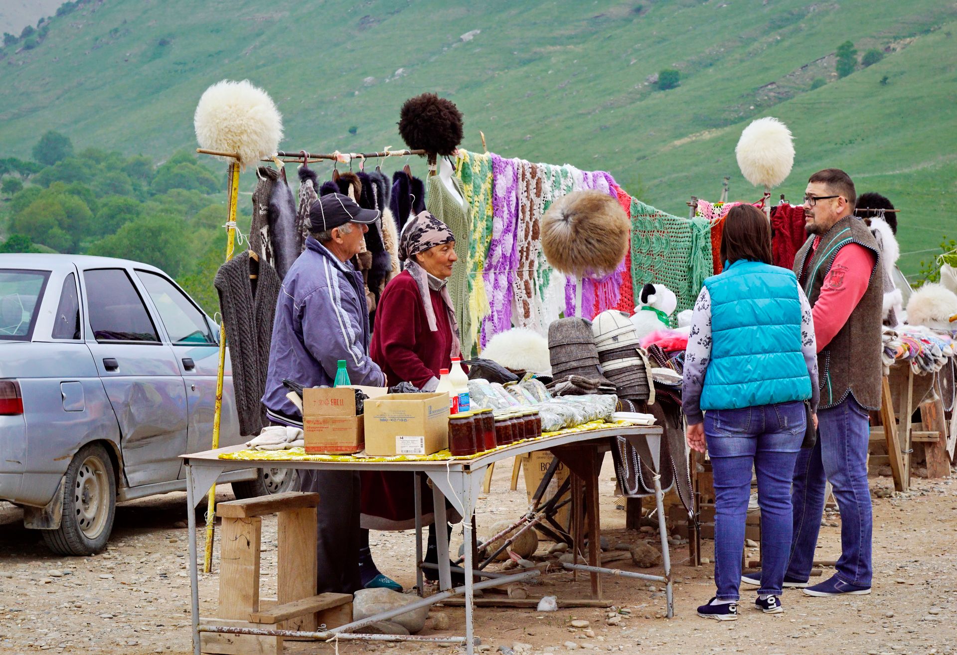 Vibrant stall at open-air market featuring handmade crafts and textiles in a picturesque setting.