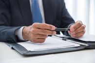 Man in Blue Suit Writing on White Paper