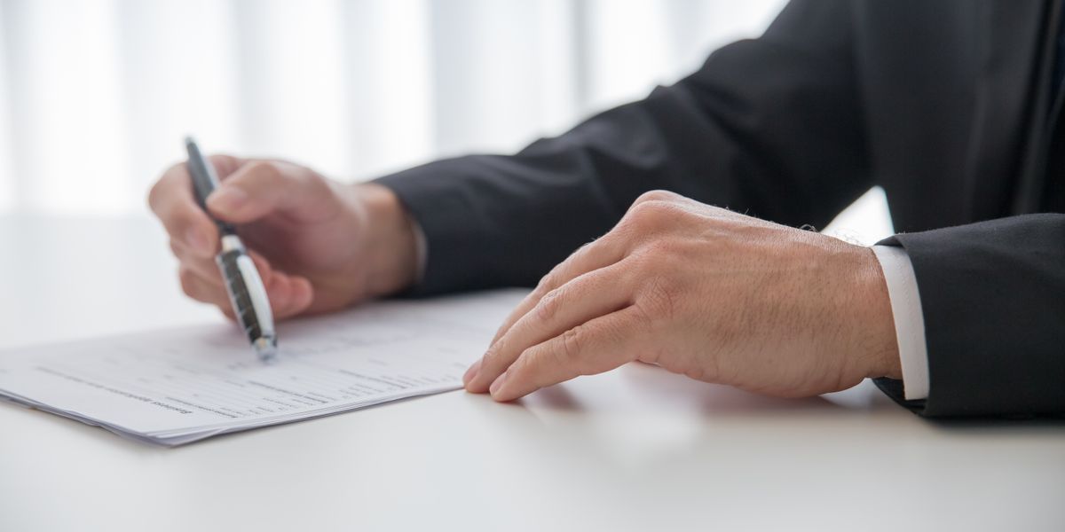 Businessman signing important documents at office desk.