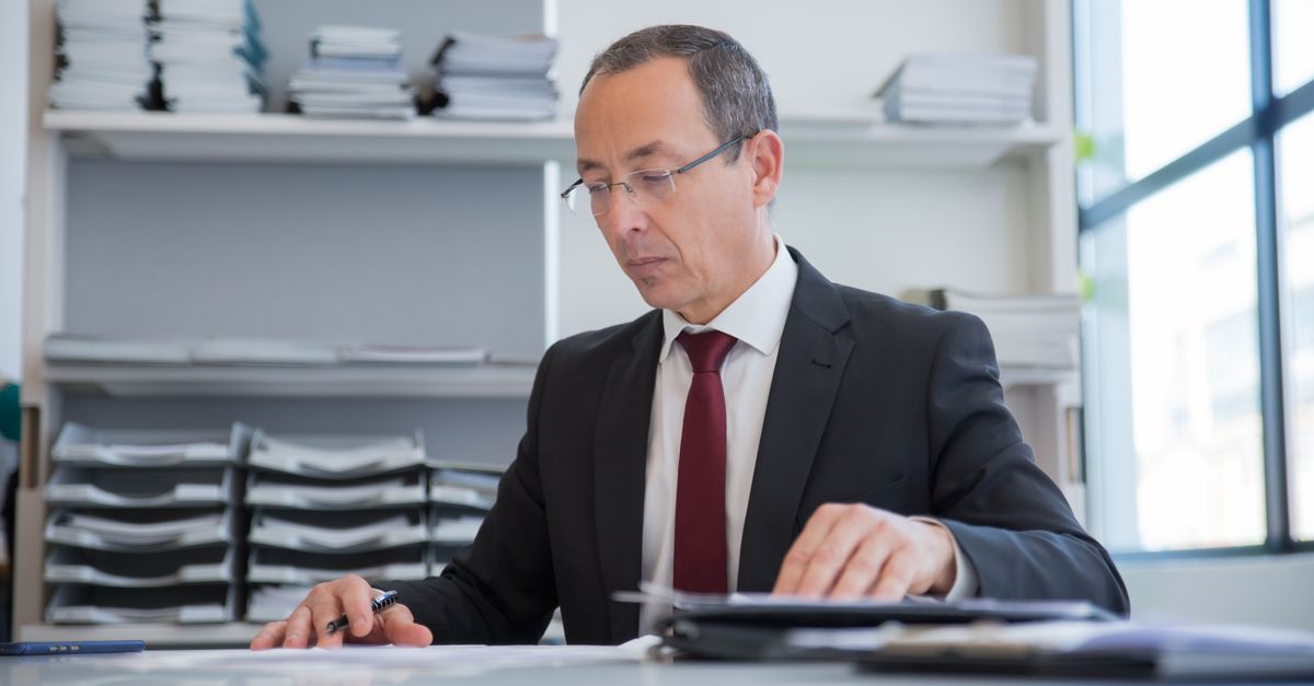 Empresario en un entorno formal revisando documentos en un escritorio.