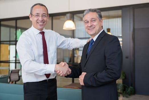 Two businessmen shaking hands in a modern office, symbolizing a successful agreement or partnership.