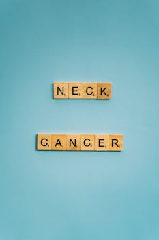 Wooden Scrabble tiles on a blue background spelling 'neck cancer'.