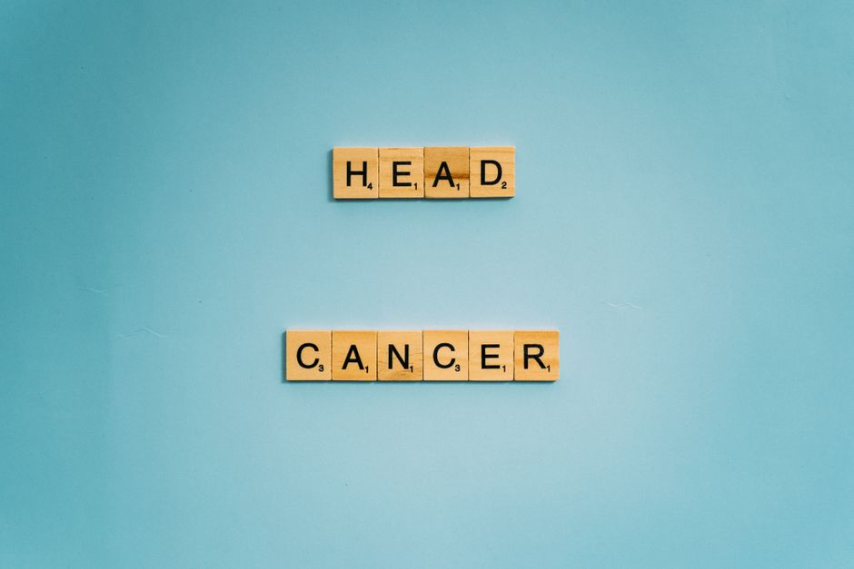 Scrabble tiles spelling 'head cancer' on blue background, promoting awareness.
