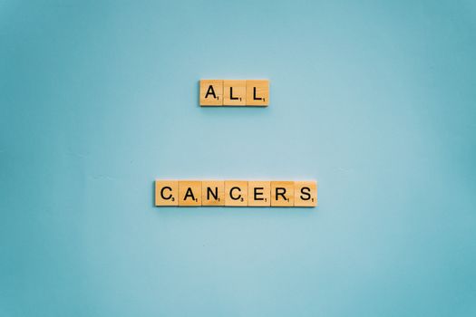 Scrabble tiles forming 'All Cancers' on a light blue background, symbolizing cancer awareness.