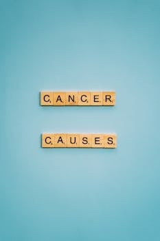 Scrabble letters spelling 'cancer causes' on a light blue background.