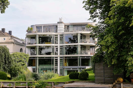 Contemporary glass facade building in Hamburg, surrounded by lush greenery.
