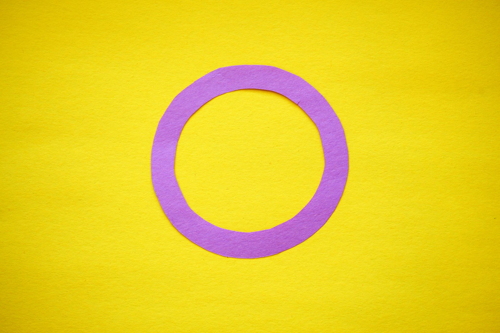 Intersex pride flag design using purple circle on yellow paper background, symbolizing inclusivity.