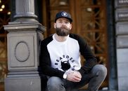 Man in White and Black Pullover Shirt Leaning on Black Post